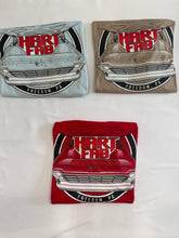 Load image into Gallery viewer, Three folded graphic T-shirts displayed on a white fabric background, each featuring a vintage car front graphic and the text 'HART FAB' and 'FREEDOM, PA'. The shirts are in light blue, tan, and red colorways.